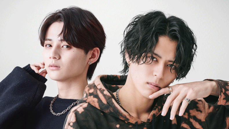 ニュアンスパーマとスパイラルパーマのセンターパートの男性2人が並んでいる