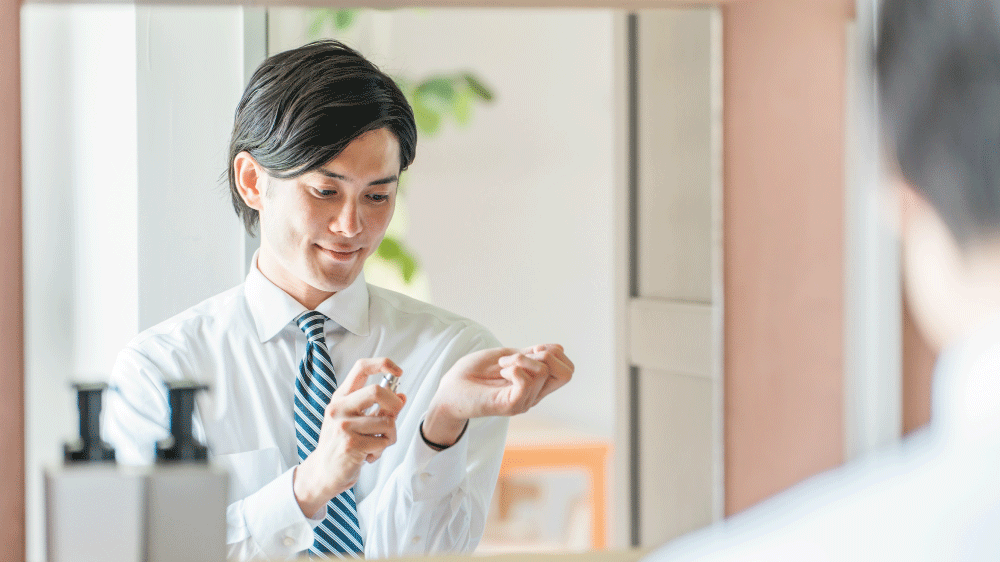 香水を手首にふりかけている男性